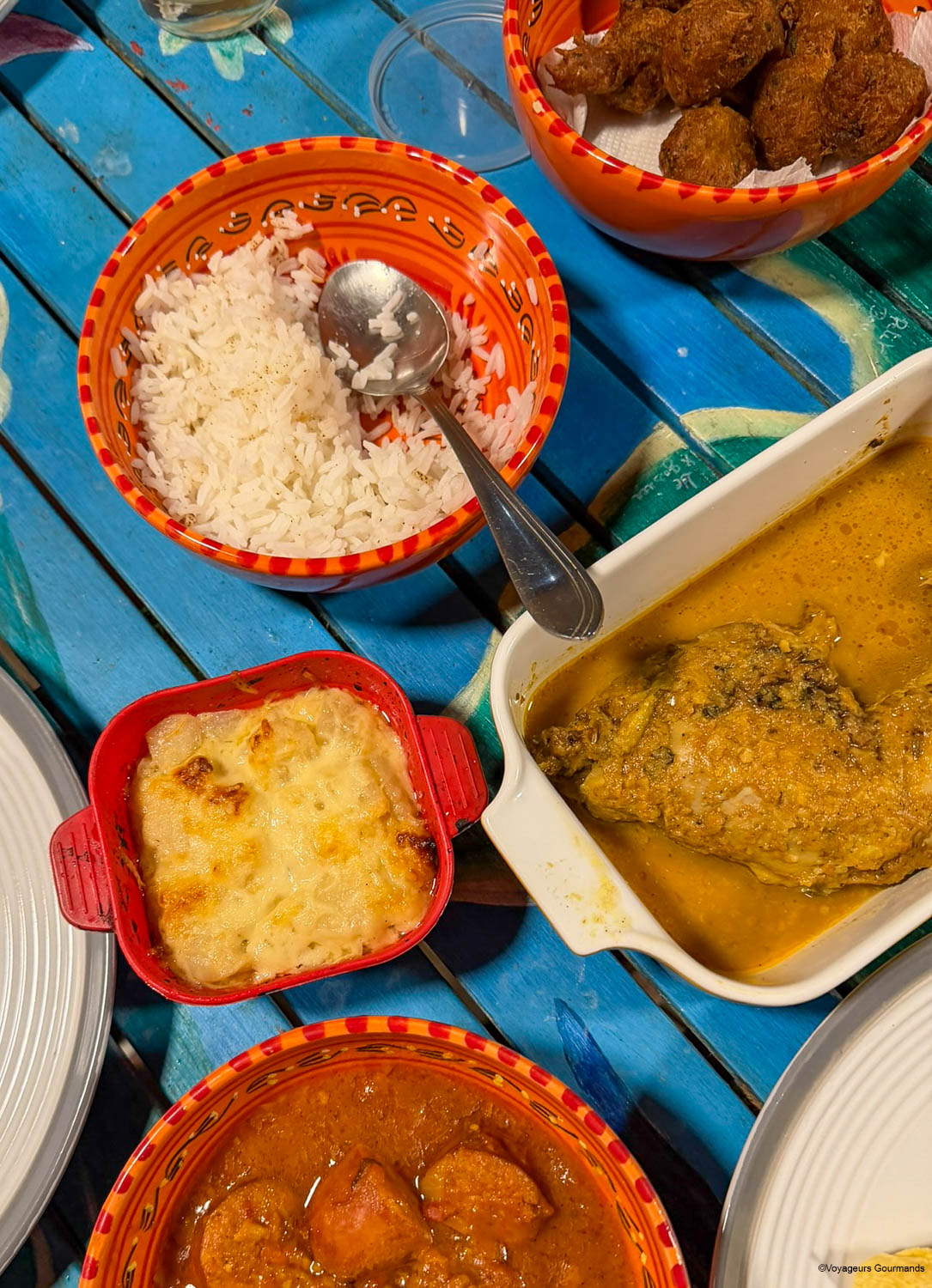 Colombo de poulet servi avec du riz blanc, un gratin et des accompagnements créoles